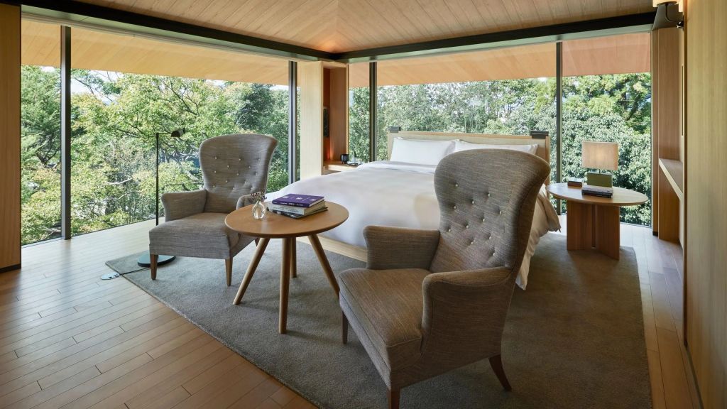 Elegantes Doppelbettzimmer mit großen Fenstern, zwei Sesseln und einem Holztisch