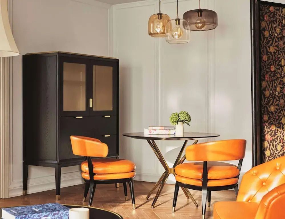 Elegante Sitzecke mit zwei orangen Sesseln und einem runden Tisch in einer Suite