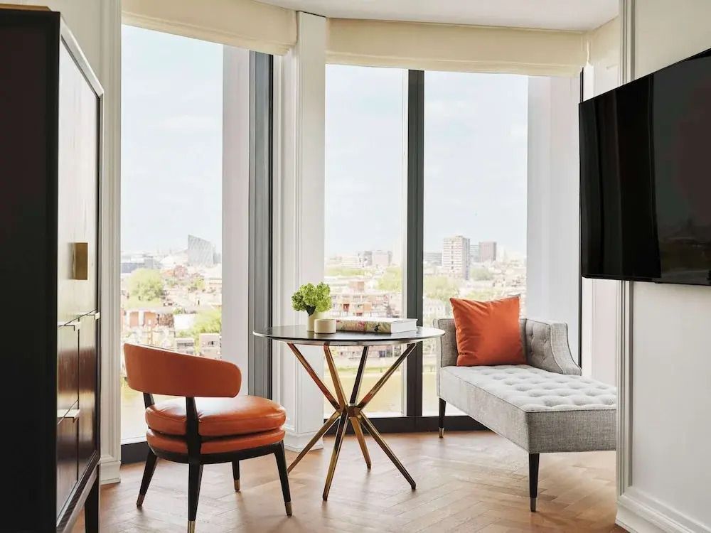 Elegantes Wohnzimmer im Hotelzimmer mit großen Fenstern und stilvollen Möbeln