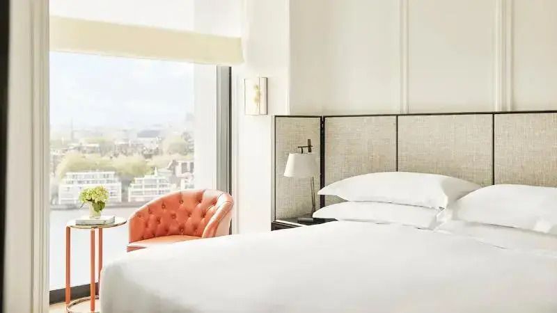 Helles Schlafzimmer mit einem großen Bett und einem eleganten Sessel