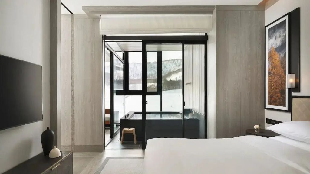 Luxuriöse Suite mit Onsen-Bad und Blick auf verschneite Landschaft.