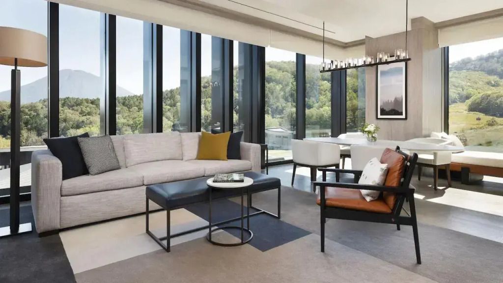Helles Wohnzimmer in Suite mit großer Fensterfront und Waldblick.