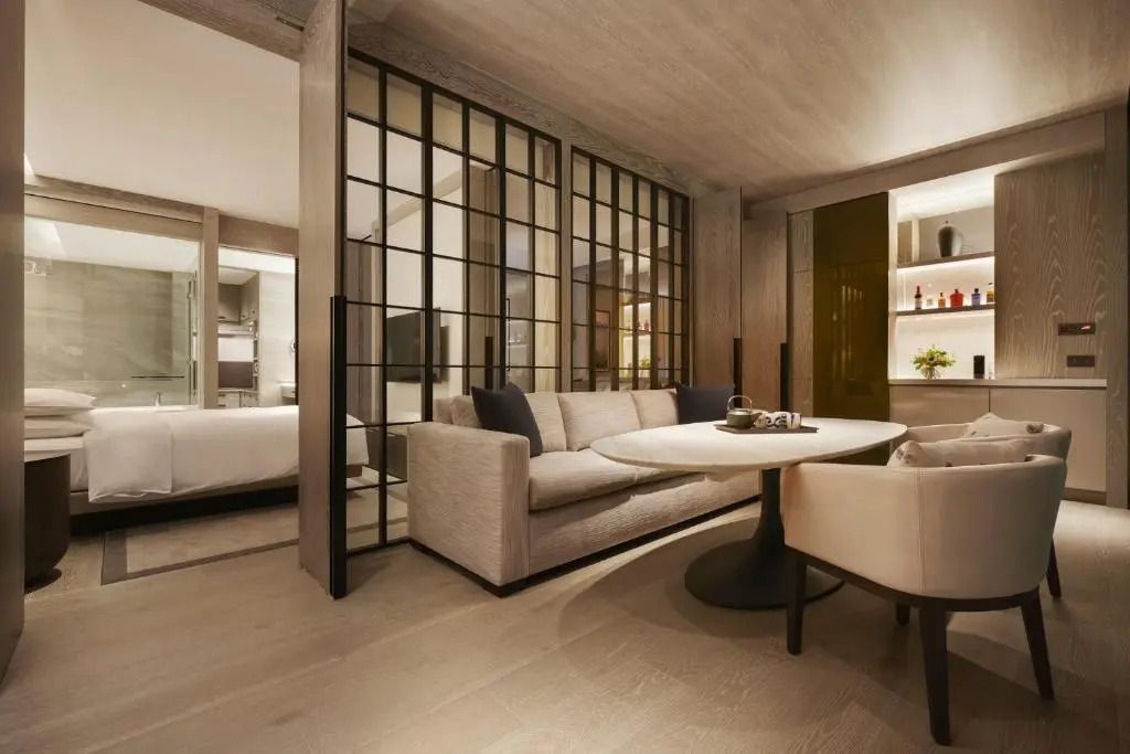 Offener Loungebereich mit Sofa und Tisch vor einer modernen Trennwand.