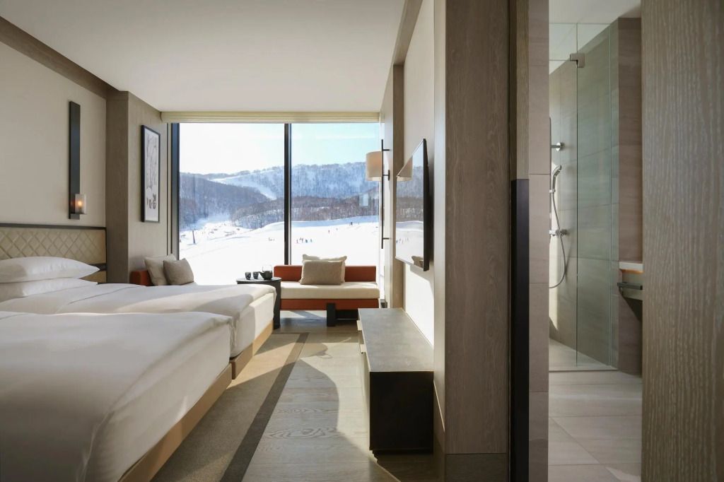 Modernes Doppelzimmer mit zwei Einzelbetten und Bergblick durch ein großes Fenster