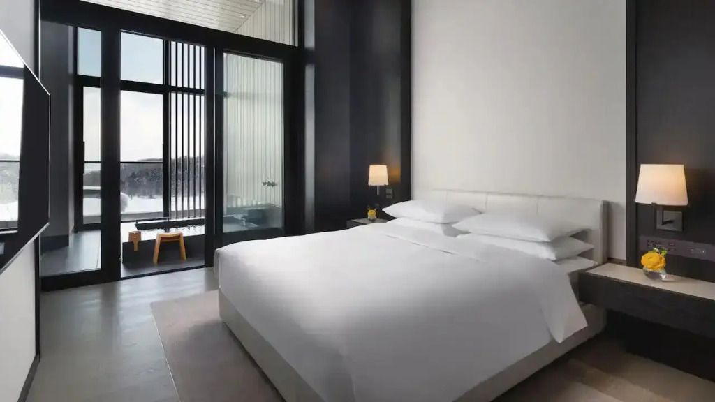 Helles Schlafzimmer mit großem Bett und Fensterfront mit Ausblick