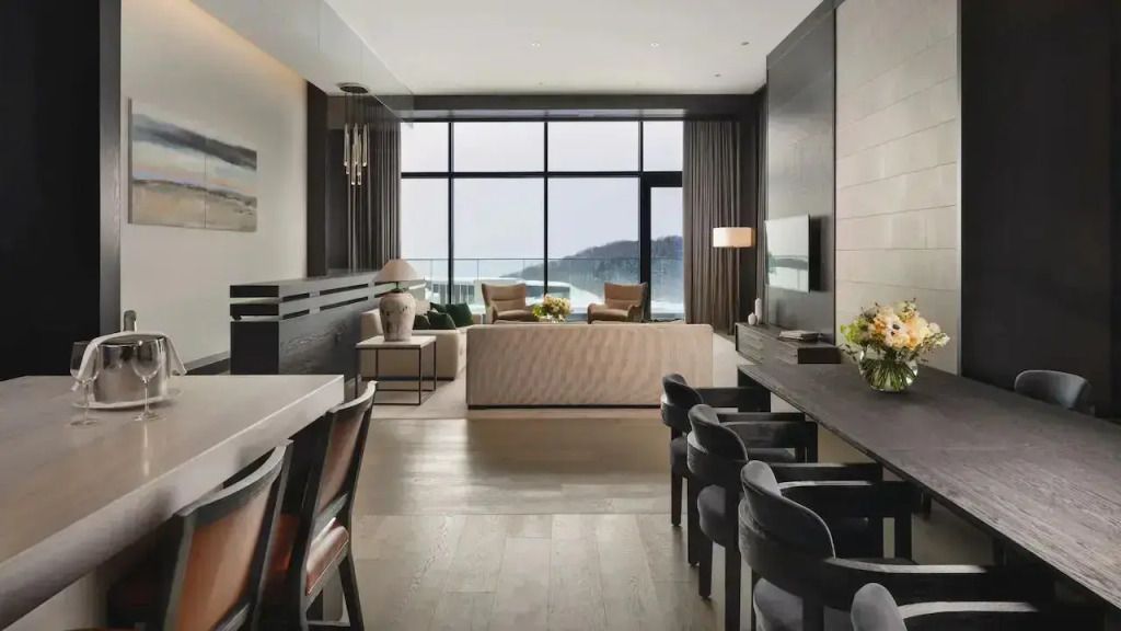 Moderne Suite mit Wohnbereich, großen Fenstern und Sitzbereich