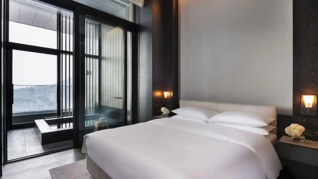 Gemütliches Schlafzimmer mit großen Fenstern und minimalistischem Design.