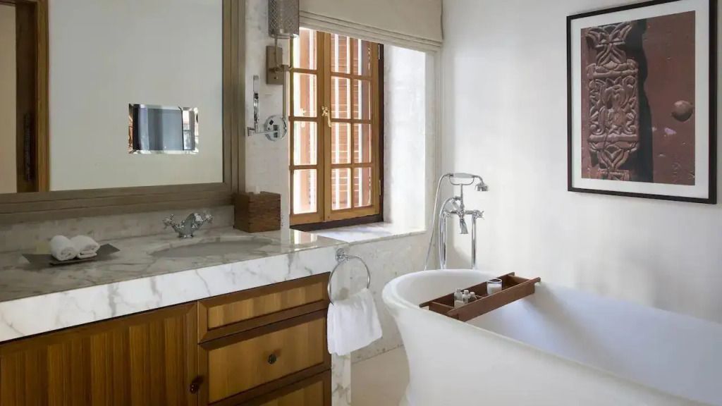 Helles Badezimmer mit freistehender Badewanne und eleganten Armaturen in der Zanzibar Suite.