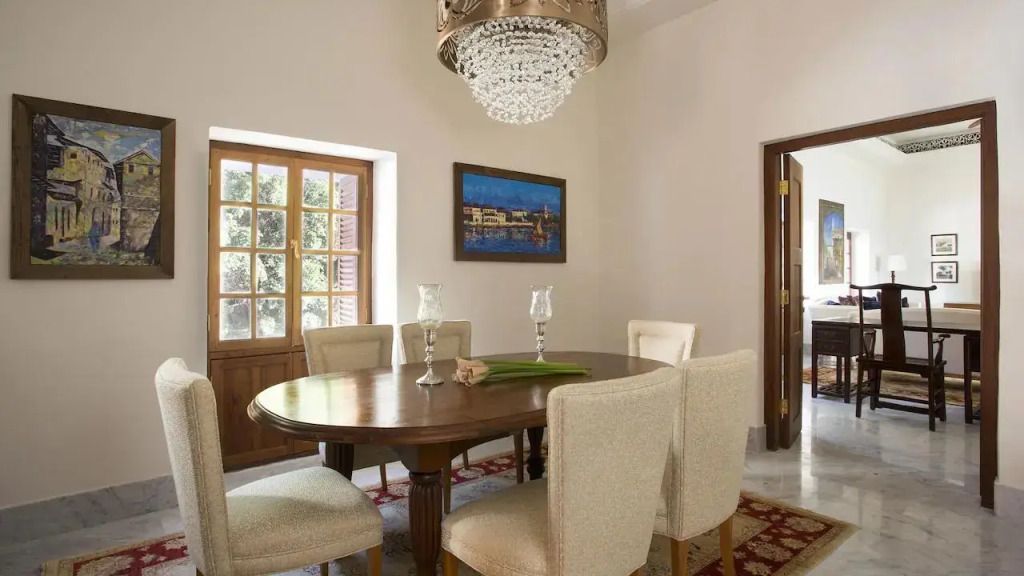 Essbereich mit Holztisch und luxuriösem Kronleuchter in der Zanzibar Suite.