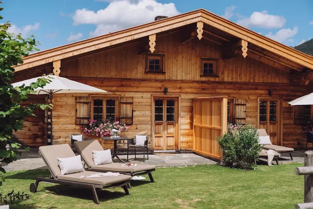 Traditionelles Holzhaus mit Liegestühlen im Garten bei sonnigem Wetter