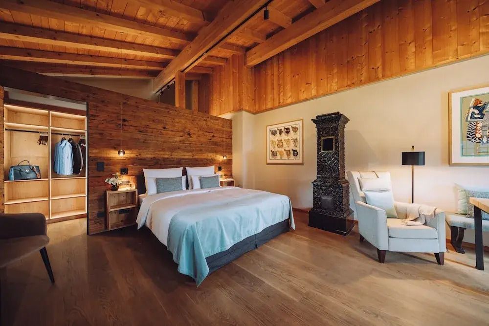 Junior-Suite mit Holzwänden, Doppelbett und traditionellem Ofen
