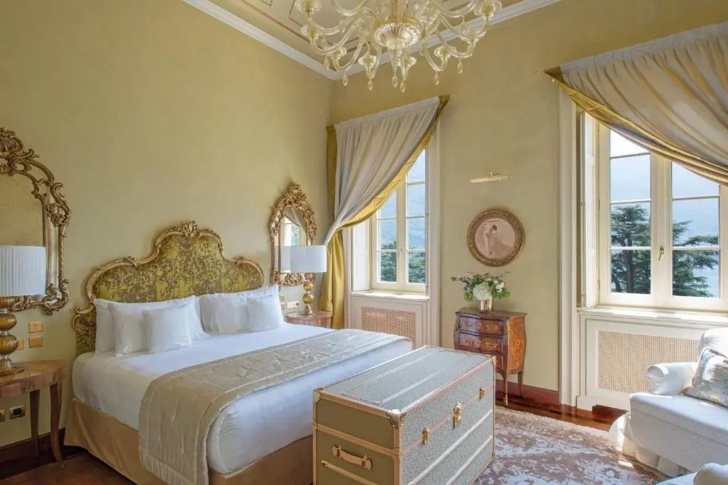 Elegantes Schlafzimmer mit großem Doppelbett und Kronleuchter, Seeblick aus den Fenstern