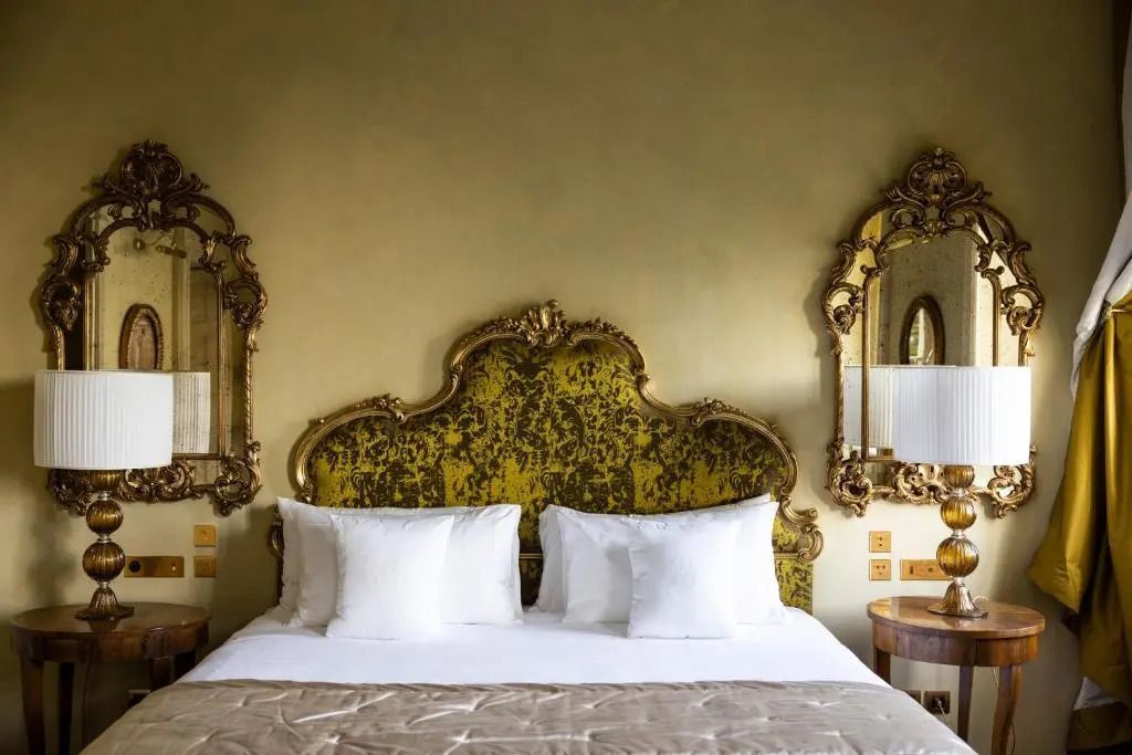 Opulentes Bett mit goldenen Akzenten und dekorativen Spiegeln an der Wand
