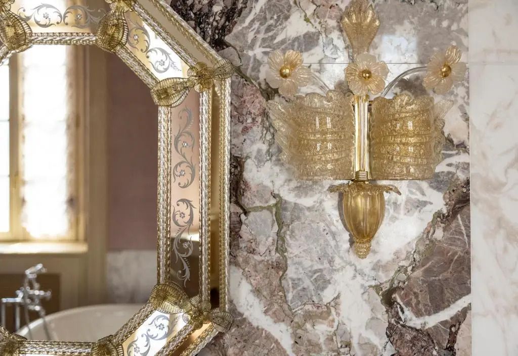 Dekorative Wandlampe und verzierter Spiegel auf gemusterter Wand