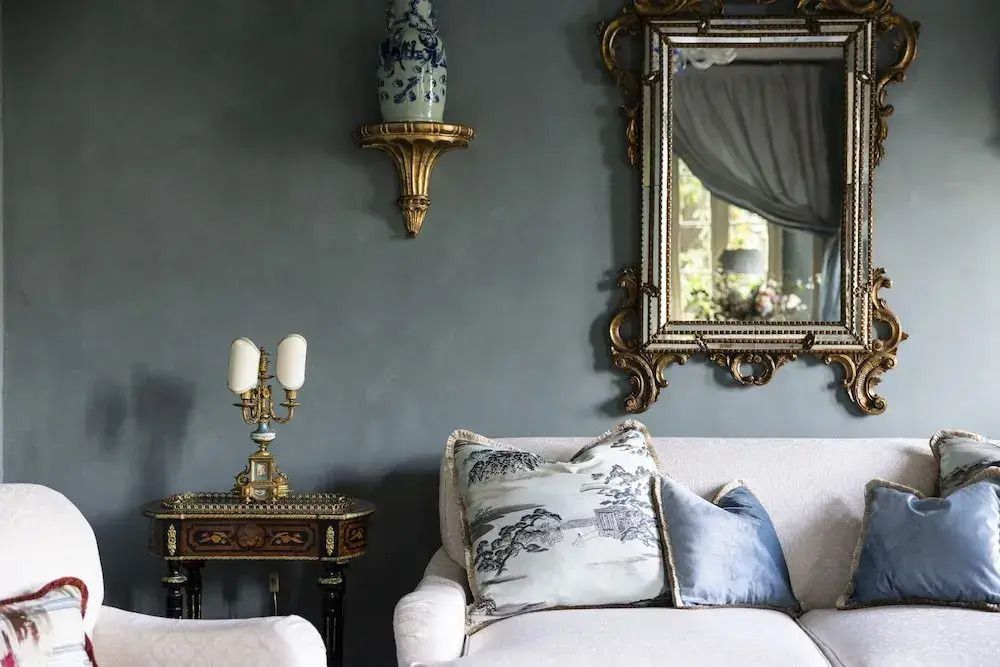 Elegantes Wohnzimmer mit verzierter Spiegelwand und luxuriösen Polstermöbeln