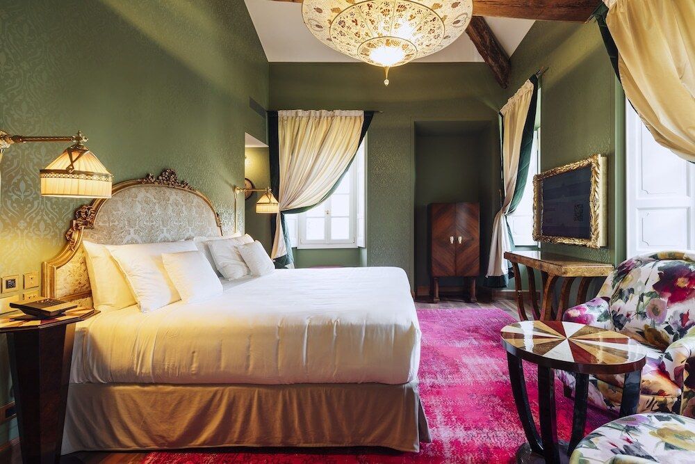 Elegantes Zimmer mit opulentem Bett, rotem Teppich und großen Fenstern mit Vorhängen
