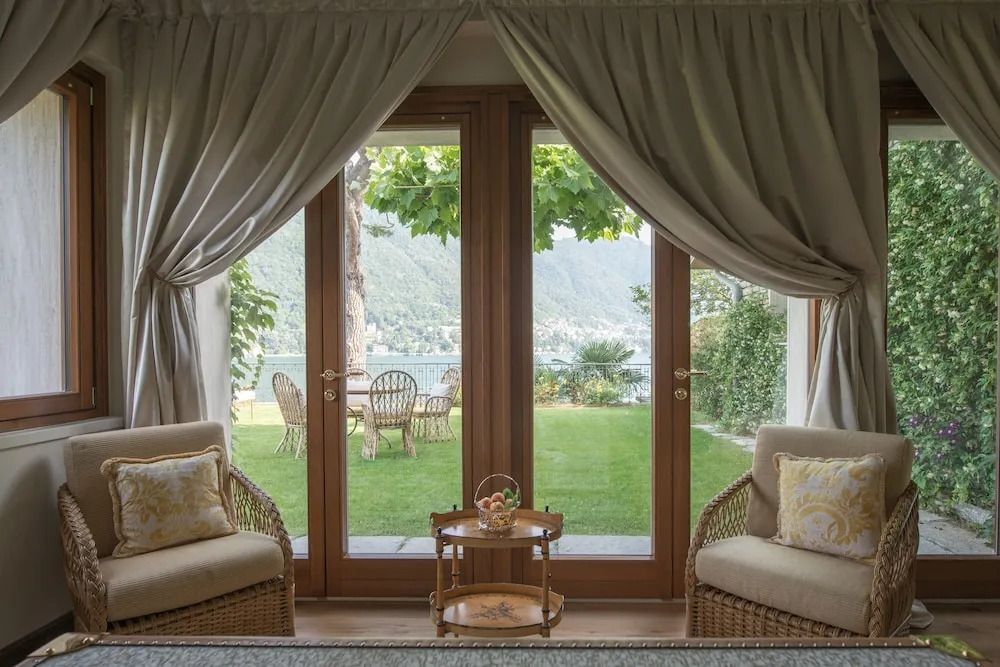 Gemütliche Sitzgelegenheit mit Blick durch Terrassentüren auf einen Garten und See