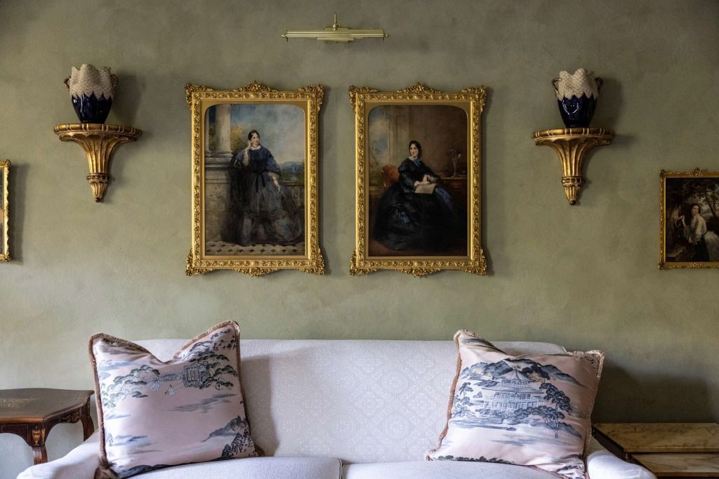 Eleganter Wohnbereich mit Gemälden und goldenen Rahmen an der Wand.