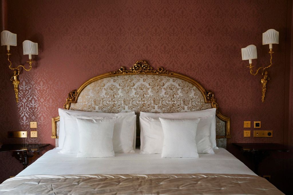Elegantes Doppelbett mit verziertem Kopfteil und weißen Kissen im Hotel Passalacqua.