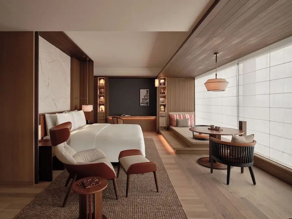 Luxuriöse Suite mit Doppelbett, Sessel und modernem Interieur.