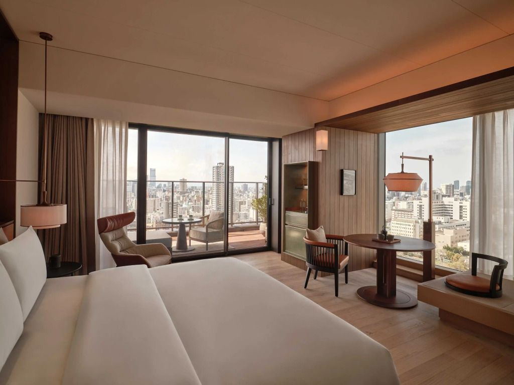 Modernes Hotelzimmer mit Doppelbett und Stadtblick von einem Balkon in Osaka.