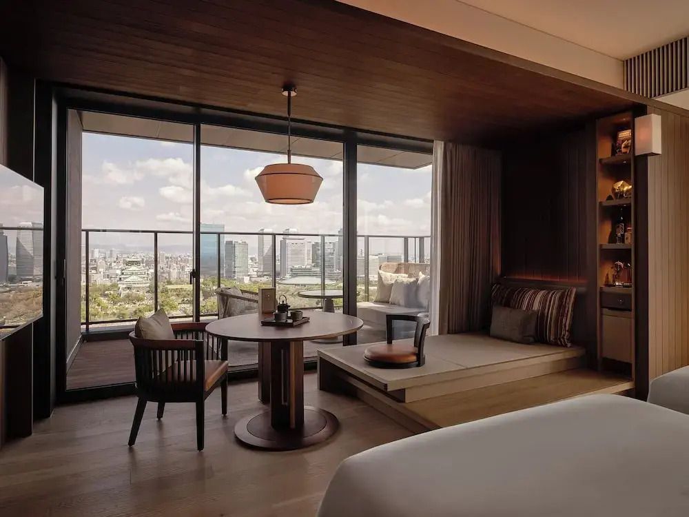 Zimmer mit großen Glasschiebetüren und Terrasse mit Blick auf Osaka Stadt.