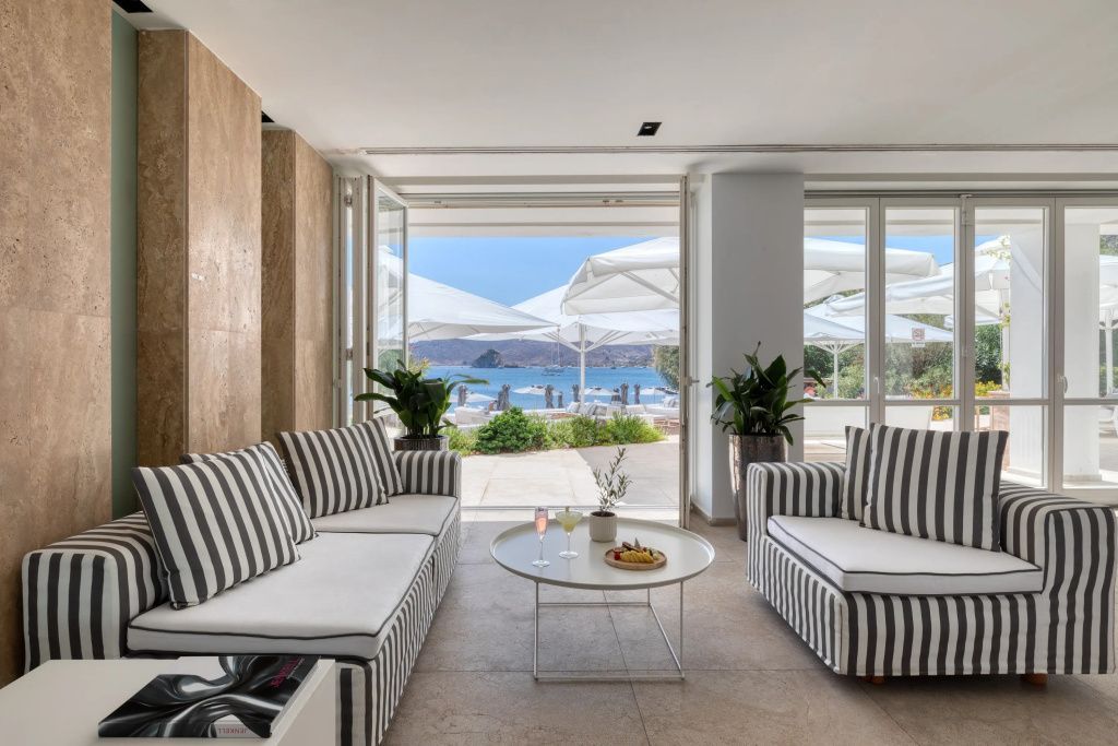 Loungebereich mit gestreiften Sofas und Panoramablick auf den Strand und das Meer.