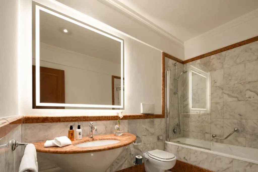 Elegantes Badezimmer mit Marmordekor und moderner Beleuchtung im Patria Palace Hotel Lecce