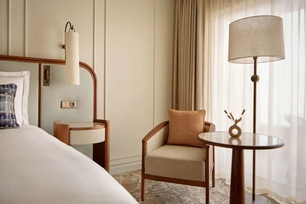 Bequemer Sessel und kleiner Tisch neben einem Bett im Deluxe Zimmer