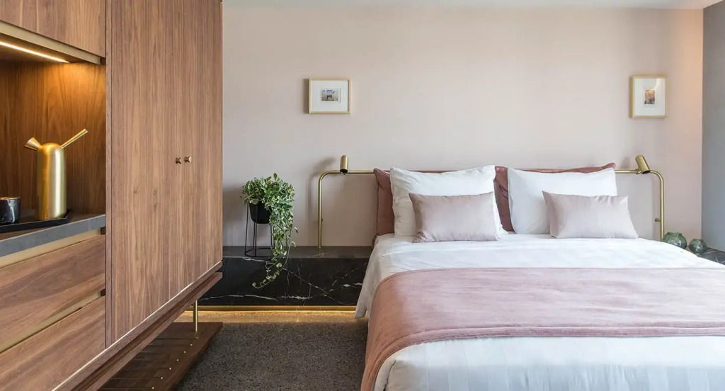 Gemütliches Doppelbett in sanften Rosa- und Holztönen