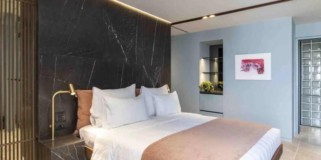 Elegante Suite mit dunkler Marmorwand und luxuriöser Bettwäsche