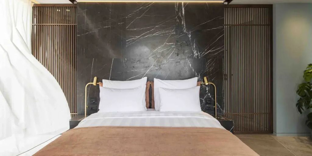 Modernes Doppelbett mit goldenen Leselampen und Marmorrückwand