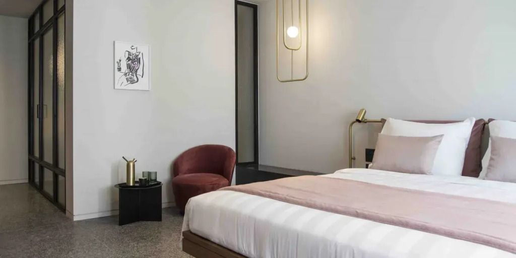Modernes Zimmer mit Doppelbett, bequemer Sessel und eleganter Beleuchtung
