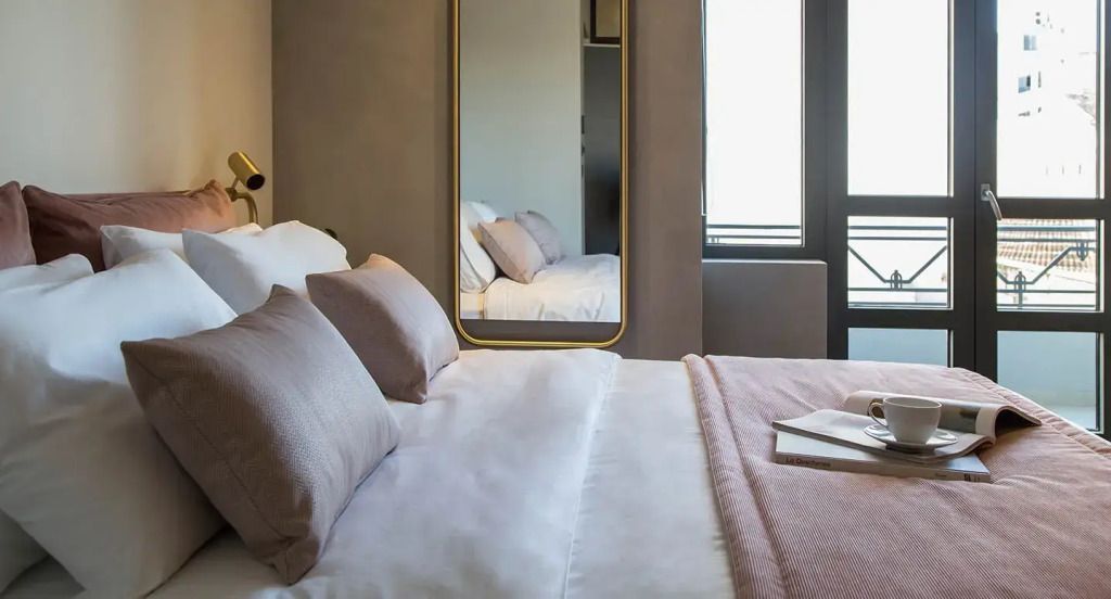 Helles Doppelzimmer mit stilvoller Einrichtung und Spiegel.