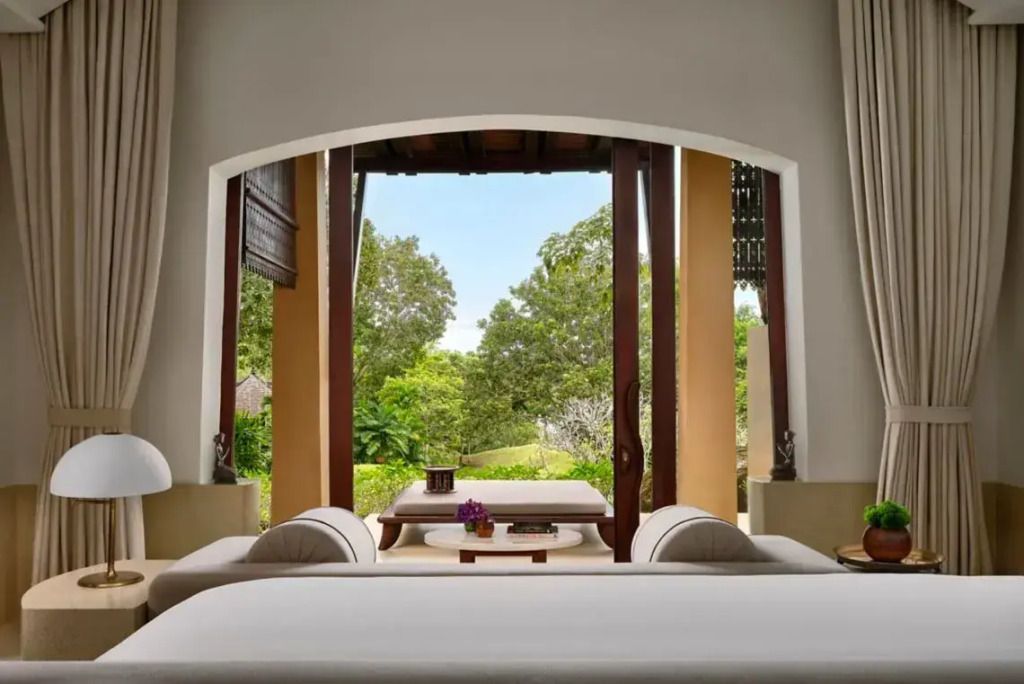 Zimmer mit offenem Ausblick auf eine grüne Gartenlandschaft durch große Fenster