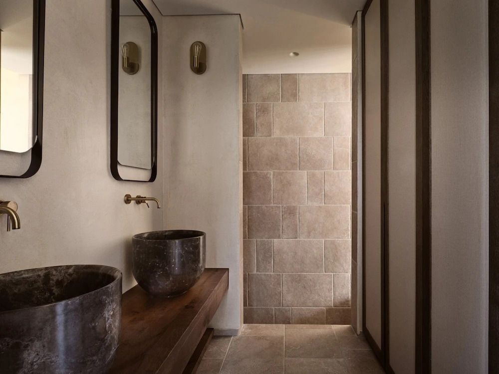 Elegantes Badezimmer mit modernen Waschbecken und großer Dusche in der Deluxe Suite