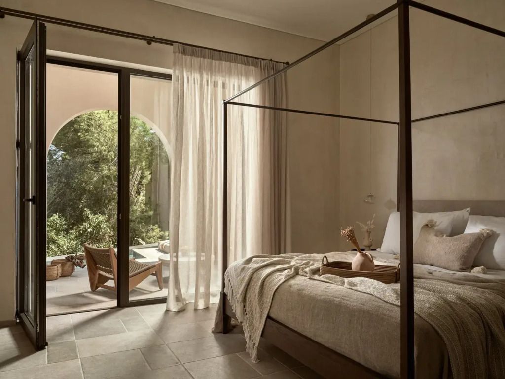 Elegante Junior-Suite mit Himmelbett und Zugang zu einem sonnigen Gartenbereich