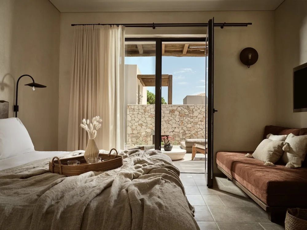 Einladendes Schlafzimmer in einer Junior-Suite mit Terrasse und Natursteinwänden