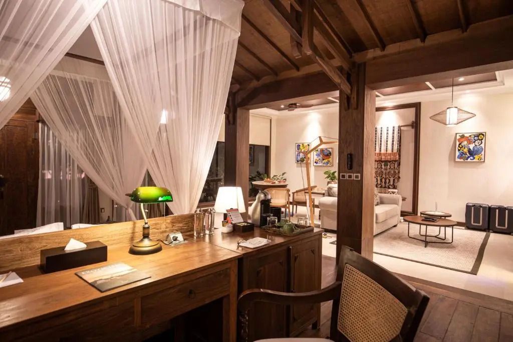 Eleganter Arbeitsbereich mit Holzschreibtisch neben Wohnbereich im Deluxe Zimmer