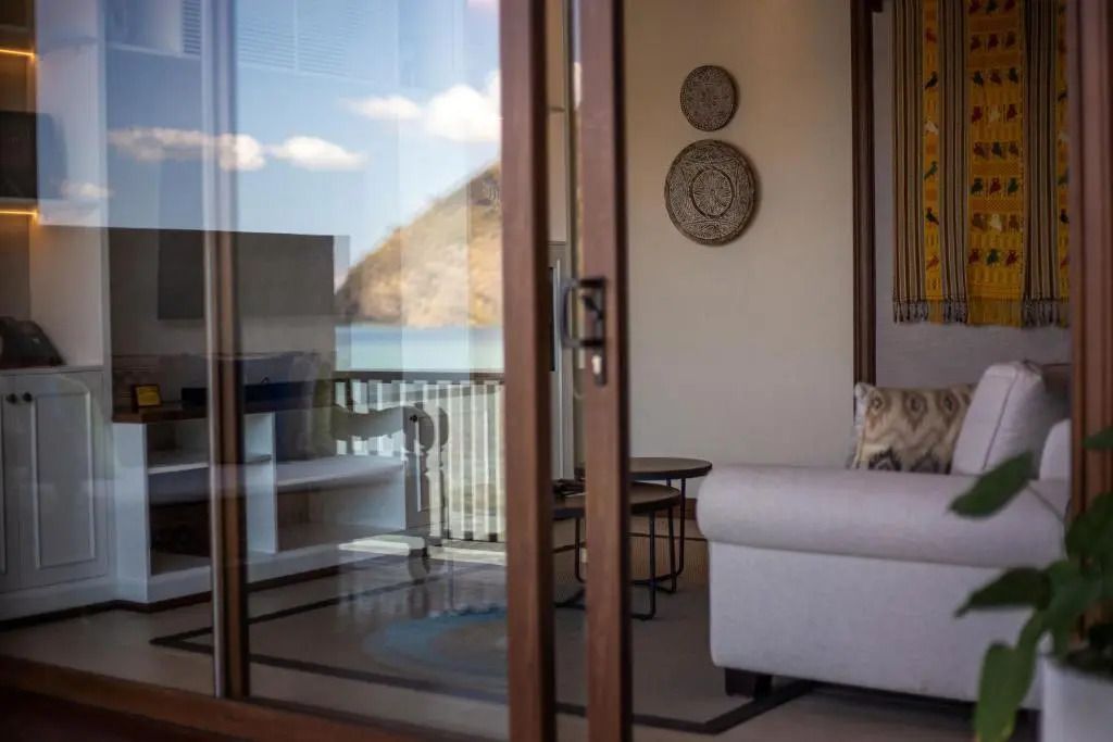 Wohnbereich mit Meerblick durch große Fenstertüren im Plataran Komodo Resort