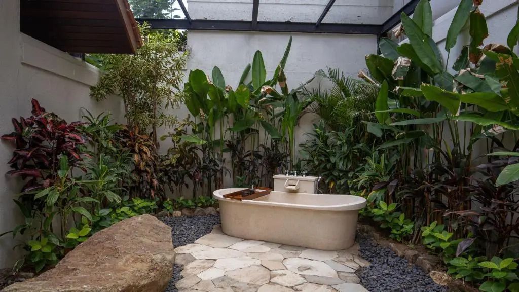 Freistehende Badewanne im Grünen in einem luxuriösen Outdoor-Bad