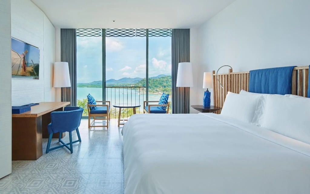 Modernes Hotelzimmer mit Doppelbett und Meerblick durch große Fenster
