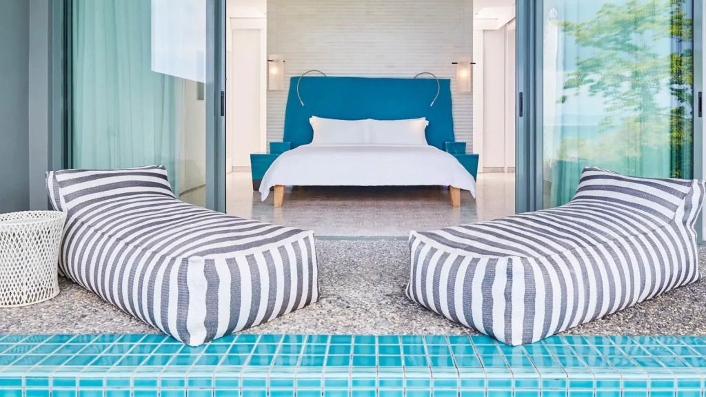 Modernes Schlafzimmer mit blauem Kopfteil und Blick auf den Pool in COMO Point Yamu