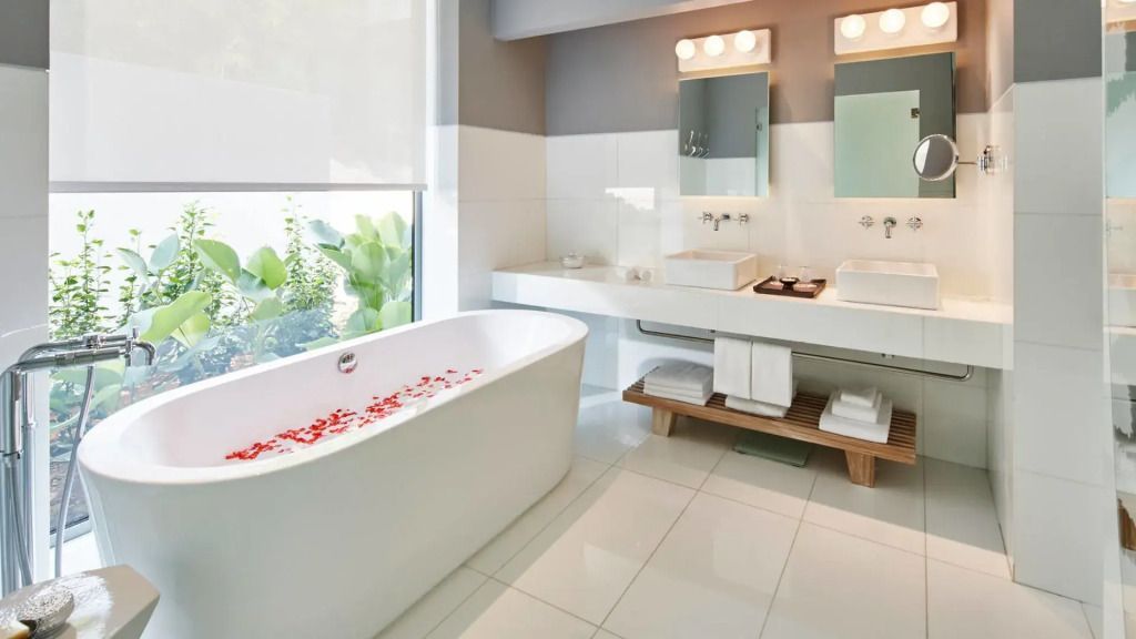 Modernes Badezimmer mit Badewanne und großen Spiegeln im COMO Point Yamu