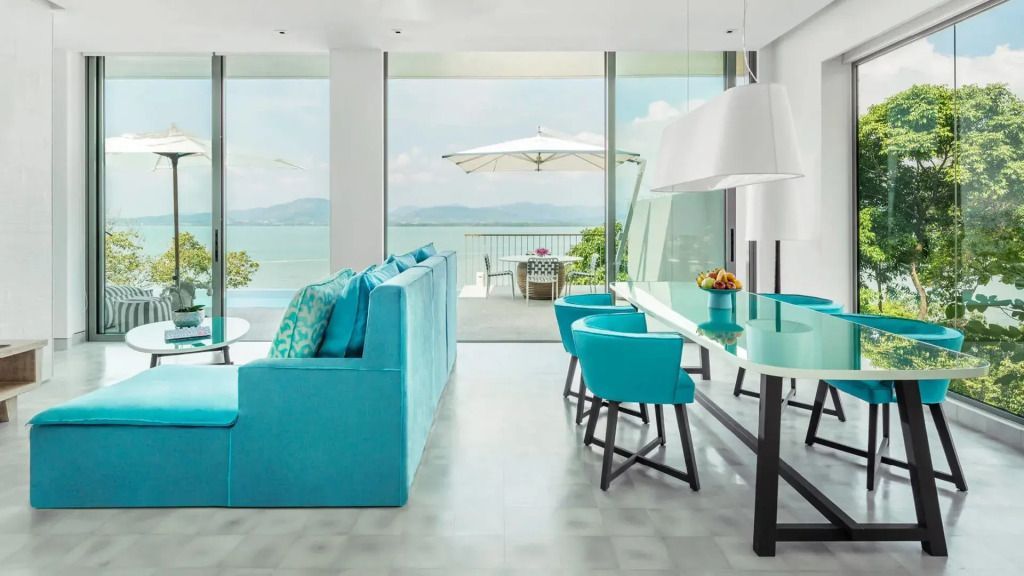 Helles Wohnzimmer mit blauem Sofa und Blick auf das Meer durch große Panoramafenster