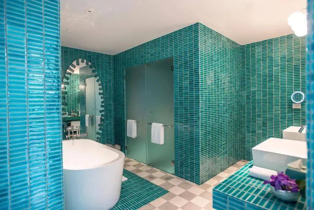 Großes Badezimmer mit türkisfarbenen Fliesen und freistehender Badewanne