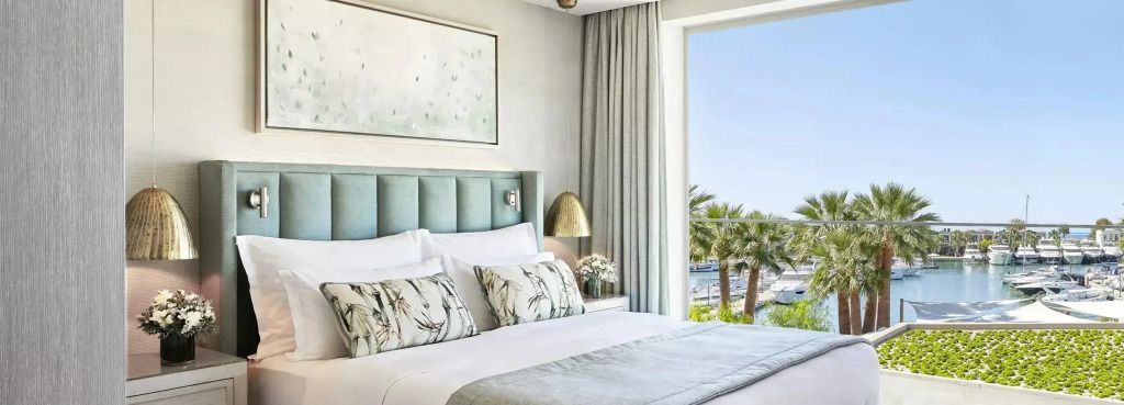 Elegantes Schlafzimmer mit großem Doppelbett und Blick auf Palmen und Meer