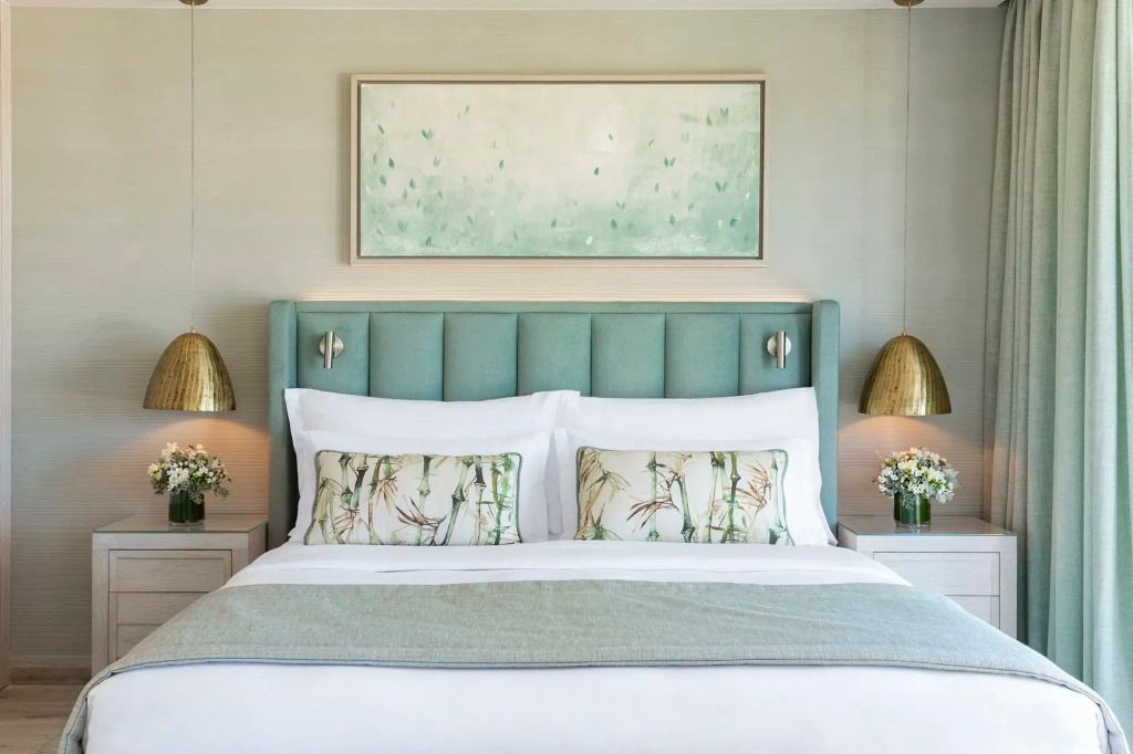 Elegantes Doppelbett mit hellblauem Kopfteil und dekorativen Kissen.