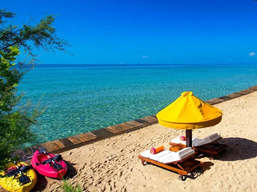 Privater Sandstrand mit gelbem Sonnenschirm und kristallklarem Meer
