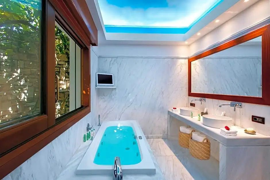 Badezimmer mit Marmorwänden und beleuchtetem Whirlpool